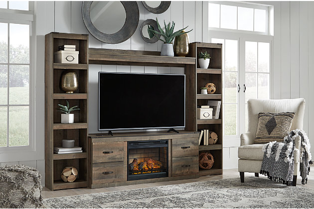 Entertain a rugged yet refined sense of style with the Trinell entertainment center. Rustic finish and plank-style details pay homage to reclaimed barn wood, while faux metal banding with nailhead accents infuses a touch of industrial cool. Ultra clean lines ensure a look that can go from the country to the city and feel equally at home. What really turns up the heat: an electric infrared fireplace insert with faux firebrick surround that operates with or without infrared heat and includes a multi flame feature, 7-level temperature setting, five brightness levels and LED glowing embers effect.Includes 2 tall piers, bridge, TV stand and fireplace insert (W100-101) | Made of engineered wood and decorative laminate | Warm rustic plank finish replicated oak grain and authentic touch | Each pier with 4 open shelves  | Dark bronze-tone hardware | TV stand with open storage area and 2 single-door storage areas (each with adjustable/removable shelf) and cutouts for wire management | Fireplace provides up to 5386 BTU/1500W and warms up to 1,000 square feet (heats larger rooms) | 7-level temperature setting, multi flame system, 5 brightness levels and LED glowing embers effect | LED flame operates with or without infrared heat | Remote control with LED display | Programmable timer will turn off the unit after a set period of time | UL Listed; power cord included | Assembly required | Estimated Assembly Time: 160 Minutes