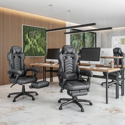 Two gray gaming chairs in an office workspace with desks and monitors