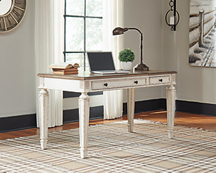 Elevating the art of traditional cottage styling, the Realyn desk is your heavenly home office realized. Antiqued two-tone aesthetic blends a chipped white with a distressed wood tone top for added charm. Framed drawer fronts, decorative corbels and elegantly turned and tapered legs add refinement, while dark bronze-tone knobs lend a classic touch. Spring lift top raises the surface to a comfortable standing position, for a healthy alternative. Built for looks and productivity, the built-in power supply and dual USB ports keep your devices close at hand and ready to go.Made of wood, engineered wood and veneers, with cast resin components | Antiqued two-tone finish | Smooth-gliding drawer with dovetail construction | Dark bronze-tone finished metal hardware | Includes AC power supply | USB charging | Spring lift top | Assembly required | Estimated Assembly Time: 15 Minutes