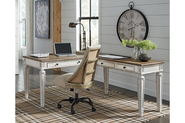Elevating the art of traditional cottage styling, the Realyn L-shaped desk is your heavenly home office realized. Two-tone finish combines chipped white with distressed wood tone tops for added charm. Framed drawer fronts, decorative corbels and elegantly turned and tapered legs add refinement, while dark bronze-tone knobs lend a classic touch.Includes desk and desk return  | Made of wood, engineered wood and veneers, with cast resin components | Antiqued two-tone finish | Return with 2 smooth-gliding drawers with dovetail construction | Desk with drop-front drawer | Return with cutout for cord management | Dark bronze-tone finished metal hardware | 2 AC electrical plug-ins and 2 USB slots | Power cord included; UL-listed | Assembly required | Estimated Assembly Time: 50 Minutes