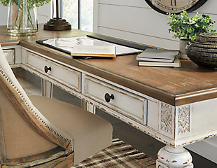 Elevating the art of traditional cottage styling, the Realyn L-shaped desk is your heavenly home office realized. Two-tone finish combines chipped white with distressed wood tone tops for added charm. Framed drawer fronts, decorative corbels and elegantly turned and tapered legs add refinement, while dark bronze-tone knobs lend a classic touch.Includes desk and desk return  | Made of wood, engineered wood and veneers, with cast resin components | Antiqued two-tone finish | Return with 2 smooth-gliding drawers with dovetail construction | Desk with drop-front drawer | Return with cutout for cord management | Dark bronze-tone finished metal hardware | 2 AC electrical plug-ins and 2 USB slots | Power cord included; UL-listed | Assembly required | Estimated Assembly Time: 50 Minutes