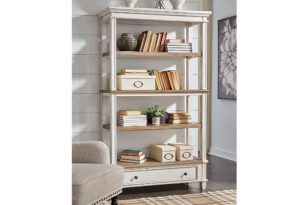 Elevating the art of traditional cottage styling, the Realyn bookcase is your heavenly home office realized. Antiqued two-tone aesthetic blends a chipped white with a distressed wood tone top for added charm. Clever balance of shelf and drawer space beautifully works.Made of wood, engineered wood and veneers | Antiqued two-tone finish | Smooth-gliding drawer with dovetail construction | 3 fixed shelves | Dark bronze-tone finished metal hardware | Estimated Assembly Time: 30 Minutes