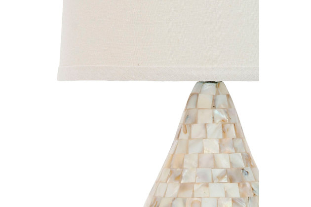 Fresh as an ocean breeze, this ivory shell table lamp set adds just the right touch of glimmer beside a sumptuously decorated bed or sophisticated sofa or chair. Crafted of natural capiz shell, the gourd-shaped base is accented with a silvertone metal neck and an off-white hardback cotton shade.Set of 2 | Made of shell and resin with fabric shade | On/off switch | Cfl bulb; 13-watt bulb included | Wipe with a soft, dry cloth; avoid use of chemicals and household cleaners as they may damage finish | Assembly required