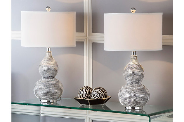 Let your room radiate in the shimmery glamour of this beaded table lamp set. Crafted of poly resin with a double gourd body, this shapely duo is completely encrusted with tiny silvertone beads. Topped with an off-white shade for clean, modern polish.Set of 2 | Made of resin with fabric shade | On/off switch | Cfl bulb; 13-watt bulb included | Wipe with a soft, dry cloth; avoid use of chemicals and household cleaners as they may damage finish | Assembly required