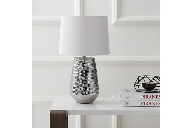 Inspired by the work of modern sculptors, this contemporary table lamp brings high style to the living room. Crafted with a subtle, delicate texture, its bold silvertone finish is refreshing and light. The tapered shade casts a welcoming glow.Made of ceramic with cotton shade | 1 type a bulb (not included); 40 watts max or cfl 13 watts max or led 9 watts | Assembly required | Clean with a soft, dry cloth