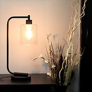 The sophistication of industrial accents gleams in this beautifully crafted iron desk lamp. The humble design combines a simple base with curved arm and a clear glass shade for the perfect ensemble. Place on a desk or bedside table for a modest, refined look in fashion lighting. **HELPFUL TIP: To get the complete industrial look, we recommend using a decorative Edison/Vintage bulb (not included). **Matte black finish | Clear glass shade | Convenient on/off cord switch | Lamp measures: l:9" x w:5" x h:19"