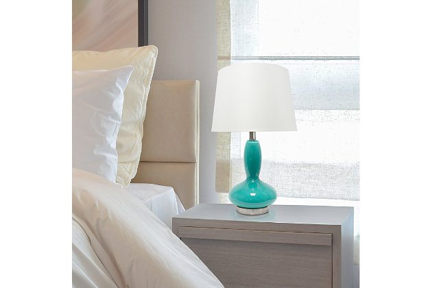 A beautiful lighting solution versatile enough for any room in your home, this contemporary lamp features a teal glass base topped with a white fabric shade.  Simplicity and style at its best!   Perfect for your living room, bedroom, office, or anywhere you need to add a tasteful update!Fabric white shade | The base is made of teal glass | 1 x 60w medium type a base bulb (not included) required | More base color options available!