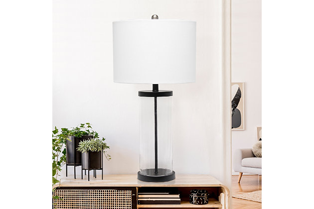 Classic yet contemporary this lamp will light up any room in your home with style!  This lamp features a clear glass cylindrical base with black metal on top and bottom for a clean, sophisticated look.   Perfect for your living room, bedroom, office, or anywhere you need to add a tasteful update!Fabric white shade | Black metal on top and bottom of clear cylindrical glass base | 1 x 100w medium type a base bulb (not included) required | More base color options available!