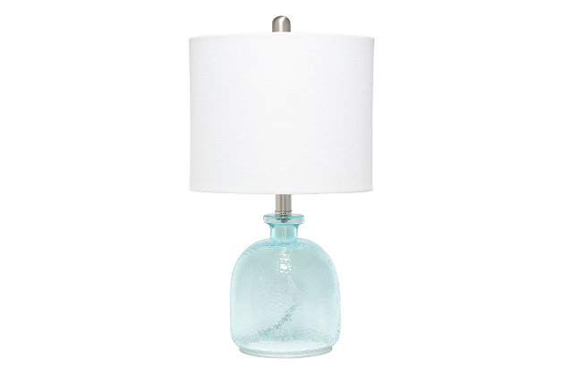 With a textured glass base and white fabric drum shade, this lamp is sure to update any room in your home with a little charm.  This lovely lamp is crafted with an open bottom glass base in a clear blue color. Perfect for adding the little refresh to your living room, bedroom, foyer or office that you've been looking for!Fabric white shade | Clear blue glass base | 1 x 60w medium type a base bulb (not included) required | More shade base color options available!