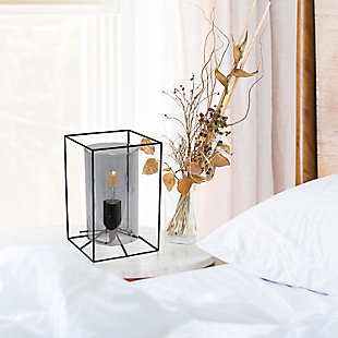This table lamp features a black metal frame with a smokey glass shade that will illuminate any room in style! The simple, clean lines of the frame is complimented by the rounded cylinder shade offering a chic sophisticated look. Perfect for your living room, bedroom, office, apartment or college dorm! **HELPFUL TIP: To get the complete industrial look, we recommend using a decorative Edison/Vintage bulb (not included). **Cylindrical smokey glass shade | Rectangular black metal frame | 1 x 40w type a base bulb (not included) required for vintage look, type t45 edison bulb is recommended | 5 foot black cord