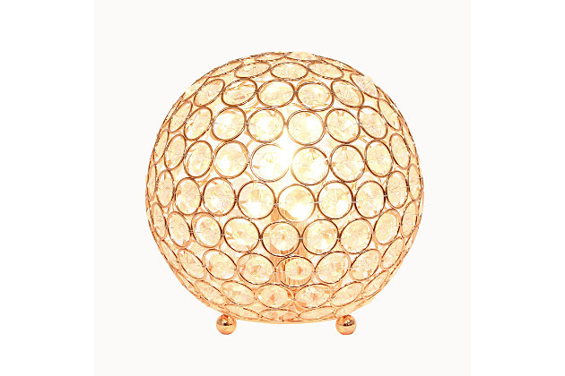 Make your room sparkle with a shining ball of crystals. The perfect addition to any bedroom, office, nursery, or even a foyer or entryway! We believe that lighting is like jewelry for your home. Our products will help to enhance your room with elegance and sophistication.Crystal ball shape glows from within casting pretty shadows | Threaded with steel rings and set on ball feet | Rose gold finish | Height: 8" diameter: 7.75"