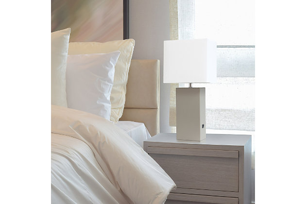 This simple yet modernized table lamp showcasing a leather body and white fabric shade is the perfect addition to your lighting needs. With a USB port on the side of the base, you are able to conveniently plug and/or charge your devide. Our products are designed to enhance your room with elegance and sophistication.Leather wrapped base with usb port | White fabric shade | Assembled dimensions: l: 10" x w: 6" x h: 21" | Uses 1 x 60w type a medium base bulb (not included)