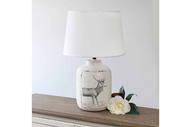 Check out this fine-looking traditionally shaped table lamp spruced with a bit of a rustic appeal.  A washed out and slightly unfinished ceramic base is decorated with a sketched deer design and paired with a white linen fabric shade.  In today's world of interior design, this lamp is the farmhouse or countryside lover's ideal lamp find.White wash ceramic base with decorative deer design | White linen empire fabric shade | Uses 1 x 60w type a medium base bulb (not included) | Easy on/off switch located on socket