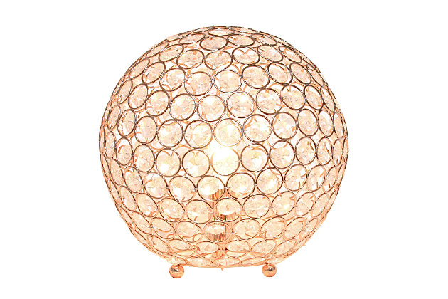 Make your room sparkle with a beautifully designed crystal ball shaped lamp. This 10" version is available in one of the many available finishes is the perfect addition to any bedroom, office, nursery, or even a foyer or entryway! We believe that lighting is like jewelry for your home. Our products will help to enhance your room with elegance and sophistication.Crystal ball shape glows from within casting pretty shadows | Threaded with steel rings and set on ball feet | Rose gold finish | Height: 10" diameter:10"