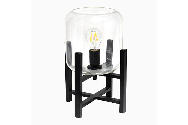This contemporary lamp elevates the glass shade on a four-arm wood stand finished in black.  The curvy cylindrical clear glass shade combined with the geometric wood base creates the perfect ensemble.  Place on a desk, nightstand, dresser or table  for a modest, refined look in fashion lighting.
**HELPFUL TIP: To get the complete vintage look, we recommend using a decorative Edison/Vintage bulb (not included). **Black wood base | Clear glass shade | Easily accessible on/off switch located on the cord | Uses 1 x 40w medium type a base bulb (not included).
For full vintage look, type t45 edison bulb is recommended