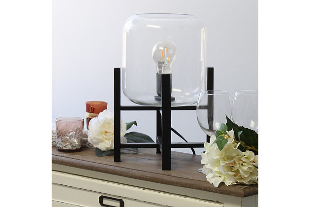 This contemporary lamp elevates the glass shade on a four-arm wood stand finished in black.  The curvy cylindrical clear glass shade combined with the geometric wood base creates the perfect ensemble.  Place on a desk, nightstand, dresser or table  for a modest, refined look in fashion lighting.
**HELPFUL TIP: To get the complete vintage look, we recommend using a decorative Edison/Vintage bulb (not included). **Black wood base | Clear glass shade | Easily accessible on/off switch located on the cord | Uses 1 x 40w medium type a base bulb (not included).
For full vintage look, type t45 edison bulb is recommended