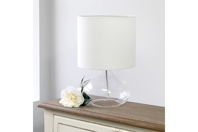 Illuminate your living space with this simple yet stylish glass table lamp.  The clear glass raindrop shaped base and white fabric drum shade is the perfect blend  of charm to give your home a contemporary and modern upgrade.  Perfect for living rooms, bedrooms, kids and teens, college dorms, apartments, nurseries, or offices.Clear glass base | White fabric drum shade | Easily accessible rotary switch located on the cord | Uses 1 x 40w medium type a base bulb (not included)