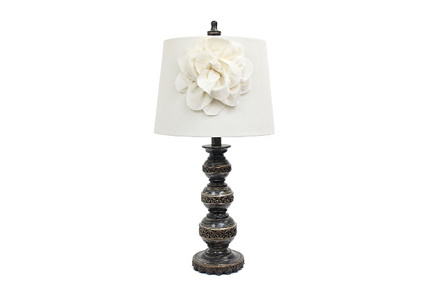 This aged bronze table lamp, with its three stacked ball base and linen shade with boutique flower adornment, will add style and pizzazz to any room. Perfect for living rooms, bedrooms, kids rooms, offices, or college dorms. We believe that lighting is like jewelry for your home. Our products will help to enhance your room with chic sophistication.3 ball stacked base with aged finish | Natural linen shade with flower adornment | Dimensions: lamp height: 25"  shade diameter: 12" | Uses 1 x 40w type a medium base bulb (not included)