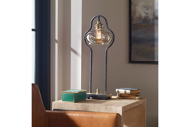 Put your decor in the best light possible with this table lamp. A curvaceous forged iron base, finished in an aged black finish, follows the contour of the light amber glass shade and is accented with brushed, antiqued brass-plated details. This lamp adds a striking look that will blend well in any living space.Made of metal, resin and glass | Metal and resin base with aged black finish | Glass shade with light amber finish | Brushed antiqued brass-plated details | On/off switch | 1 bt58 antique-style bulb; 60 watts (included)