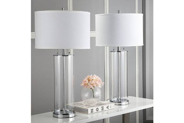 The epitome of style and substance, this clear modern glass table lamp offers world-class sophistication. Its contemporary spin on art deco style blends sleek chrome-tone detail with the clean lines of its off-white cotton shade. A modern classic.Set of 2 | Made with metal; 100% cotton shade | Includes 4 CFL bulbs | 13W max | On/off switch  | 5' cord | Assembly required | Imported