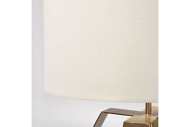 This meticulously crafted table lamp features a geometric, hollow slated base. A cream colored fabric lampshade sits atop the metal base adding to the beautiful design of the lamp while helping to cast a soft ambient glow wherever it's placed. Flaunting clean lines and a minimalist design complemented by its radiant finish, this accent lamp is the perfect addition to any elegant space and setting.Made of metal with modified drum fabric shade | Goldtone finish | Single E26 bulb (not included); 60 watts max; UL Listed | Indoor use only | Assembly required | Imported