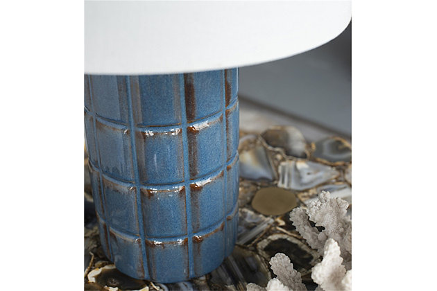 This cylindrical table lamp features a rectangle press pattern for a craft aesthetic that can't be beat. Finished in a rich vintage blue tone, the ceramic base is perfectly complemented with a white drum shade for a pulled together aesthetic. Add this lamp to tabletops in your living room, dining room or anywhere else that needs a splash of color.Made of ceramic with fabric drum shade | Blue finish | Rotary switch | 1 type E26 bulb (not included); 60 watts max; UL Listed | Indoor use only | Imported | Assembly required