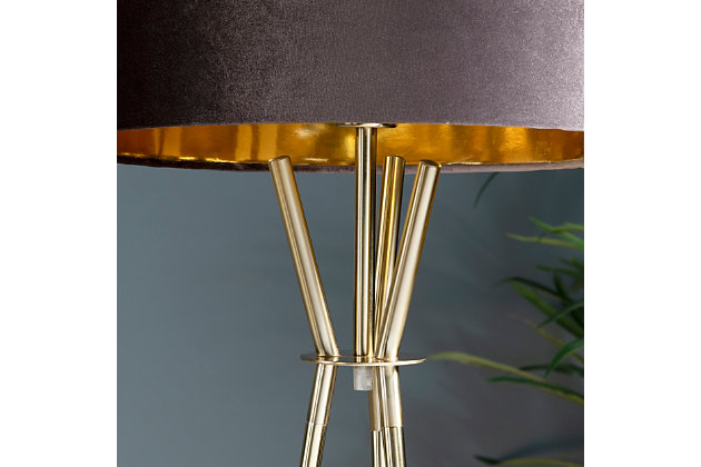 Embrace the power and beauty of the Emerson tripod floor lamp. It marries a sleek goldtone base with a taupe velvet drum shade for a brilliant look. Bringing light to your space in elegant style, this lamp is perfect for adding a final touch of contemporary charm.Made of iron with hardback drum velvet shade | Goldtone powder coat finish | On/off foot switch | 1 E26 socket; type A bulb recommended (not included); 150-watt max | Non-skid bottom | Power cord included; UL Listed | Assembly required