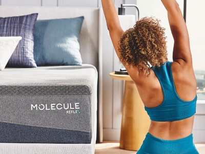 Athlete stretching beside mattress in showroom