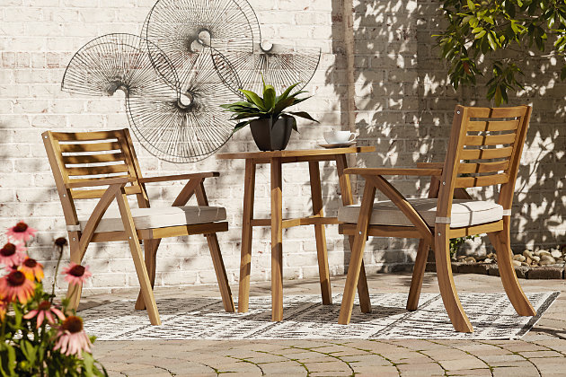 Turn an outdoor space into your own private oasis with the Vallerie 3-piece bistro set. The essence of easy-breezy outdoor living, this brilliantly styled bistro set is quality crafted of acacia wood in a natural teak tone for an exotic element. Delightfully low-maintenance seat cushions wrapped in Nuvella® fabric perfect the aesthetic.3-piece outdoor furniture set includes table and 2 chairs with cushions | Made of teak-tone acacia wood with slatted styling | Cushion covered in solution-dyed Nuvella® (polyester) high-performance fabric | All-weather foam cushion core wrapped in soft polyester | Clean fabric with mild soap and water, let air dry; for stubborn stains, use a solution of 1 cup bleach to 1 gallon water | Imported fabric and fill | Assembly required | Estimated Assembly Time: 30 Minutes