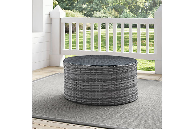 Stylish and functional. This round coffee table, composed of all-weather resin wicker elegantly woven over a durable powdercoated steel frame is topped with a tempered glass surface. Great on its own or paired with the rest of your outdoor decor, this table rounds out your outdoor space perfectly.Made of steel, resin wicker and tempered glass | Gray faux rattan over steel powdercoat frame | Weather resistant | Assembly required
