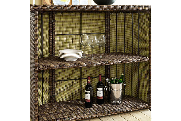 Raise the bar on al fresco living with this portable outdoor bar table. Allowing you to bring entertaining poolside, on the patio, deck or garden space with ease, the ample serving surface, tempered glass tabletop and shelf storage come together to create the ultimate outdoor bar area. Crafted from weather resistant, high-quality round wicker and a powdercoated steel frame, this is an outstanding choice for your outdoor entertaining space.Made of steel, resin wicker and tempered glass | Weathered brown faux rattan over steel powdercoat frame | 2 open shelves | Uv resistant resin wicker | Assembly required