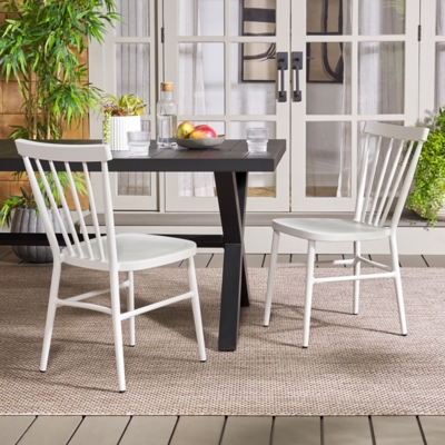 Two white outdoor dining chairs with a table and accessories.