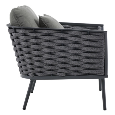 Side view of the armchair showing woven sides and thin metal legs.