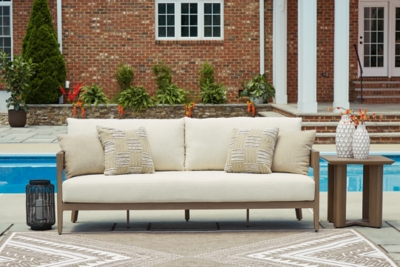 Close-up of beige outdoor sofa with throw pillows by pool