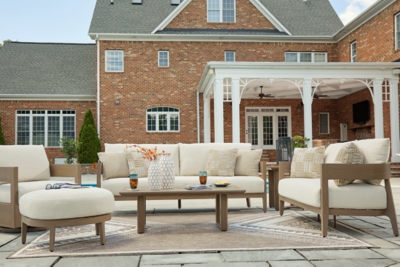 Backyard patio with beige outdoor sofa set and coffee table in front of brick house