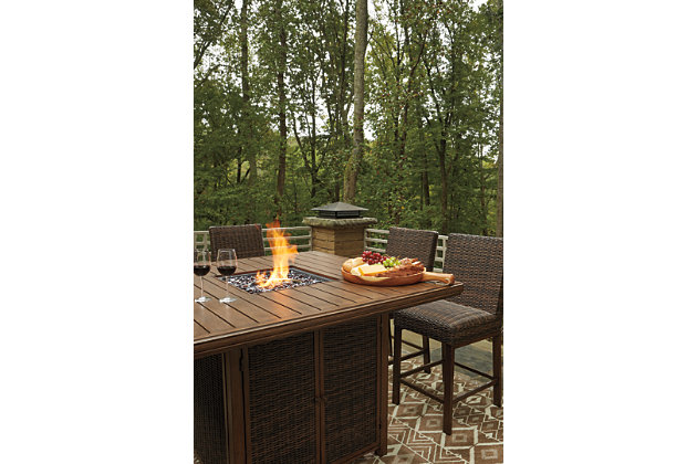 Turn your backyard space into your own piece of paradise with the Paradise Trail 9-piece outdoor fire pit table set. Though this outdoor table looks remarkably like wood, it’s made of sturdy, rust-proof aluminum that’s perfectly suited for al fresco living. Enhancing the rustically refined aesthetic: all-weather, handwoven resin wicker. The result may look high maintenance, but rest assured, this outdoor fire pit table set is anything but. With the press of a button, ignite a flickering flame that dances over a bed of glass beads. And with eight high-style bar stools, it’s one highly accommodating outdoor bar table set.Includes square bar table with fire pit and 8 bar stools | Bar stools with all-weather, handwoven resin wicker over rust-proof aluminum frame; legs with wood-like finish | Fire pit table with rust-proof aluminum frame, wood-look tabletop and side panels accented with all-weather, handwoven resin wicker | 56" square fire pit table with CSA-approved 50,000 BTU stainless steel burner, glass beads, burner cover and enclosed storage area with shelves | Battery-operated ignition system with adjustable flame control; battery included | Convertible to natural gas | Table comes with protective weather cover | Door conceals gas propane tank (not included) | Assembly of fire pit table provided with in-home delivery; connection to propane tank or connector hose not provided
 | Estimated Assembly Time: 180 Minutes