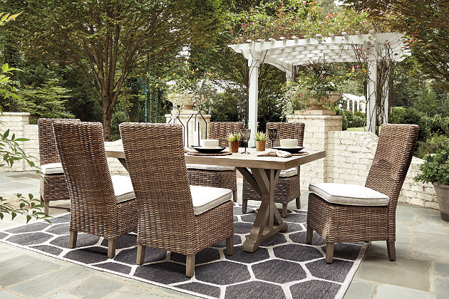 Sporting an easy-on-the-eyes look inspired by driftwood, the Beachcroft dining set elevates the art of alfresco living. Beautiful and durable enough for indoor or outdoor use, the table and chairs blend high style with low maintenance. The table charms with X-leg farmhouse styling and a thick porcelain table top that’s a natural complement. The brilliantly styled chair entices with a plush, removable cushion wrapped in high-performing Nuvella® fabric that’s a breeze to keep clean.Includes dining table and 6 side chairs | Table with all-weather, rust-resistant, powder coated aluminum base and frame; porcelain table top | Chairs with all-weather resin wicker handwoven over powder coated rust-resistant aluminum frame | Stainless steel hardware | Cushion covered in Nuvella® (solution-dyed polyester) high-performance fabric  | All-weather foam cushion core wrapped in soft polyester | Table comfortably accommodates 6-8; features umbrella hole and cover cap (umbrella not included) | Clean fabric with mild soap and water, let air dry; for stubborn stains, use a solution of 1 cup bleach to 1 gallon water | Designed to withstand the harsh elements of the outdoors | Imported fabric and fill | Assembly required | Estimated Assembly Time: 120 Minutes