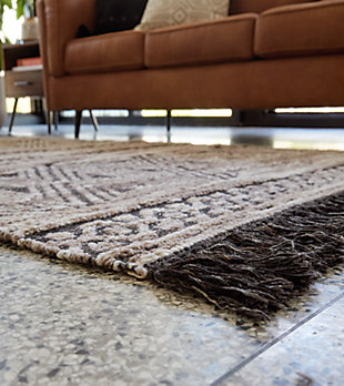 Dare to be different. Warm up your classic decor with the Kylin tribal-inspired area rug. This rug features a taupe and black palette with flirty fringe accents that add a bit of rustic flair to the flatwoven construction.Made of polyester/wool | Backed with cotton | Handwoven jacquard | No pile | Spot clean only | Rug pad recommended | Imported