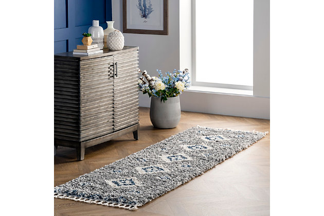 Step into comfort with the luxuriously soft and fluffy texture of this rug that simply has it all. You are sure to enjoy its contemporary style, plush pile, and braided tassel edges. The perfect addition to any space in your home that needs a touch of style and comfort, you may just find yourself relaxing directly on this rug. Machine-made of polypropylene to ensure durability and ease of care.100% polypropylene | High pile (1.5") | Step into comfort with the soft and fluffy texture of a shag rug | The perfect cozy rug for your bedroom, living room, or hallway | A neutral color palette with pops of blue make this rug fun and unique | Fresh and of the moment, this contemporary rug adds the right amount of chic to your space | Includes 3" braided tassels on both ends | Imported