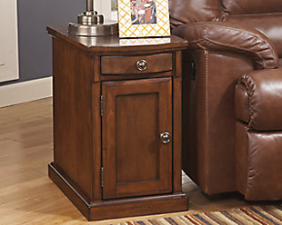 So much form and function in a beautifully compact piece of furniture. The richly styled Laflorn chairside end table puts it all within reach, including a flip-up top panel revealing a power port—perfect for keeping your phone or laptop charged. Hidden twin cup holders and interior shelved storage are also a welcome surprise.Hand-finished | Made of veneers, wood and engineered wood | Assembly required | 1 cabinet with 1 adjustable shelf | Pull-out tray with 2 recessed cup holders and remote control slot | Flip-top compartment with 3 electrical outlets, 2 USB slots | Power Cord, UL listed | Aged bronze-tone hardware | Excluded from promotional discounts and coupons