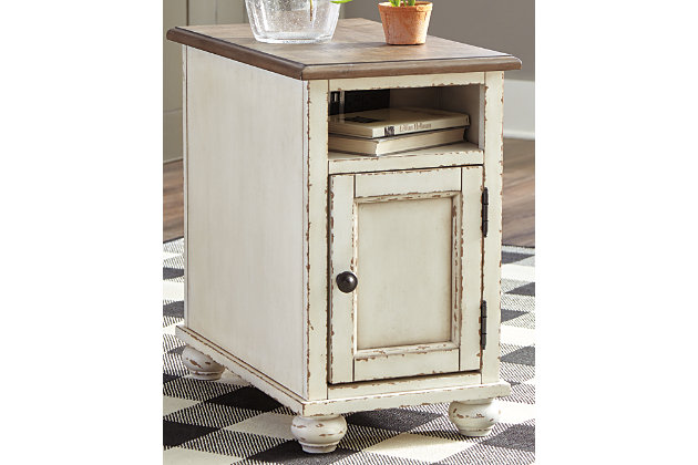 The Realyn chairside end table is traditional cottage styling made for modern living. Antiqued two-tone finish blends a chipped white with a distressed wood finished top for a double serving of charm. Cleverly placed AC power outlets and USB charging ports are beautifully in tune with your high-tech needs.Made of wood, engineered wood and veneers | Antiqued two-tone finish | Open display shelf | Cabinet storage with shelf | Dark bronze-tone finished metal hardware | 2 electrical outlets and USB charging ports | Power cord included; UL Listed | Assembly required | Estimated Assembly Time: 15 Minutes
