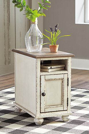 The Realyn chairside end table is traditional cottage styling made for modern living. Antiqued two-tone finish blends a chipped white with a distressed wood finished top for a double serving of charm. Cleverly placed AC power outlets and USB charging ports are beautifully in tune with your high-tech needs.Made of wood, engineered wood and veneers | Antiqued two-tone finish | Open display shelf | Cabinet storage with shelf | Dark bronze-tone finished metal hardware | 2 electrical outlets and USB charging ports | Power cord included; UL Listed | Assembly required | Estimated Assembly Time: 15 Minutes