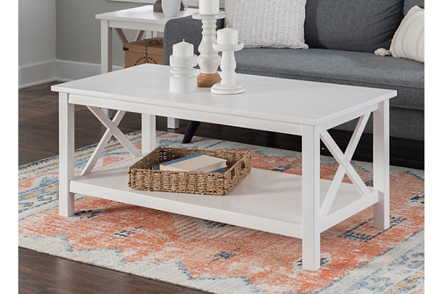 This sturdy coffee table makes itself at home in living rooms of all shapes and styles. A welcoming and versatile centerpiece, you can use its wide, smooth surface to showcase your favorite display items or serve trays of food when guests come over. The large lower shelf offers extra storage, and the crisscross sides add interest to this modern farmhouse piece. It is crafted from solid pine with an antique white finish that allows the beauty of the wood grain to show through. It also works perfectly as a media stand holding a TV, plus ample space below.Welcoming centerpiece with large, versatile surface | Modern farmhouse design that compliments any style | Crafted from solid pine with subtle wood grain under the antique white finish | Large lower shelf provides extra storage | Classy X design on sides | Can also work perfectly as a media stand | Part of a collection | Easy to assemble | Weight Limit: 30 lbs on Top, 15 lbs on Shelf | Top Dimension: 44" x 22", Shelf Dimension: 39" x 19.12", Distance from floor to bottom of item: 3.87"