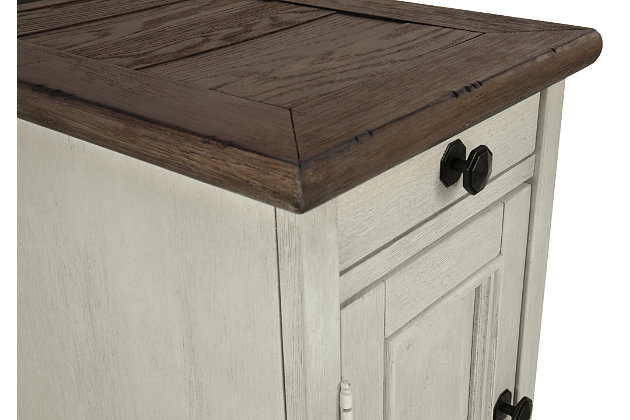 Display and contain your favorite things with the Bolanburg end table. Its textured antique white finish creates a vintage two-tone look, while outlets and USB ports provide functionality. This is a piece you will enjoy for years to come.Made of veneers, wood and engineered wood | Two-tone antiqued finish | Metal hardware | Pull-out tray | Single cabinet storage | Lift-top back revealing 2 electrical outlets and 2 USB charging stations | Power cord included; UL Listed | Minor assembly required