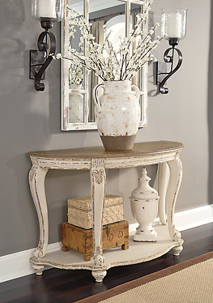 Elevating the art of traditional cottage styling, the Realyn demilune sofa table is sure to serve you beautifully for years to come. Antiqued two-tone aesthetic blends a chipped white with a distressed wood finished top for added charm. Classic cabriole legs and shapely lower shelf are a lovely twist. Decorative corbels add refinement.Made of veneers, wood and engineered wood, with cast resin components | Antiqued two-tone finish | Fixed lower shelf | Assembly required | Estimated Assembly Time: 15 Minutes