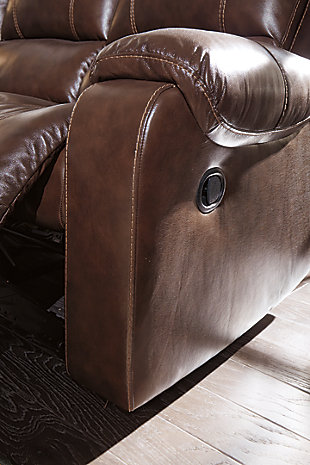 Once you recline in the Rackingburg rocker recliner with the pull of a tab, you will not want to get up. It's that comfortable with a bustle back and padded ottoman. Its look is amazing with dramatic cut and sew lines, jumbo stitching and affordable mahogany leather match upholstery, which features top-grain leather in the seating areas with skillfully matched vinyl everywhere else—what a way to relax.Bustle back | Attached cushions | Corner-blocked frame with metal reinforced seat | Pull-tab reclining motion | Leather interior upholstery/polyester and vinyl exterior upholstery | High-resiliency foam cushions wrapped in thick poly fiber