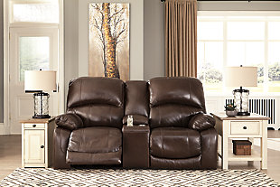 Fashion-forward style. Sumptuous leather feel and appeal. Total comfort at your fingertips. It’s all yours for the ta with the Hallstrung power reclining loveseat with console. Wrapped in a rich chocolate brown upholstery, this decidedly contemporary power loveseat tantalizes the senses in so many ways. Rest assured, the seating area is covered in 100% leather for your pleasure, while a skilly matched faux leather on the exterior makes luxury affordable. Upping the comfort with 44" high back styling, this power loveseat truly caters from head to toe. An Easy View™ power adjustable headrest allows you to lean back while propping up your head—perfect for chilling out in front of the TV—while an extended ottoman lets you stretch out all the more. And with a USB port in each power control panel, you hardly have to move a muscle to stay powered up.Dual-sided recliner | One-touch power controls with adjustable positions | Corner-blocked frames with metal reinforced seats | Easy View™ power adjustable headrests | 44" high back design | Attached backs and seat cushions | High-resiliency foam cushions wrapped in thick poly fiber | Leather interior upholstery; polyester/vinyl upholstery | Lift-top storage console and 2 stainless steel cup holders | Extended ottomans for enhanced comfort | Includes USB charging port in each power control | Power cord included; UL Listed | Estimated Assembly Time: 15 Minutes