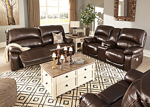 Fashion-forward style. Sumptuous leather feel and appeal. Total comfort at your fingertips. It’s all yours for the taking with the Hallstrung power reclining loveseat with console. Wrapped in a rich chocolate brown upholstery, this decidedly contemporary power loveseat tantalizes the senses in so many ways. Rest assured, the seating area is covered in 100% leather for your pleasure, while a skillfully matched faux leather on the exterior makes luxury affordable. Upping the comfort with 44" high back styling, this power loveseat truly caters from head to toe. An Easy View™ power adjustable headrest allows you to lean back while propping up your head—perfect for chilling out in front of the TV—while an extended ottoman lets you stretch out all the more. And with a USB port in each power control panel, you hardly have to move a muscle to stay powered up.Dual-sided recliner | One-touch power controls with adjustable positions | Corner-blocked frames with metal reinforced seats | Easy View™ power adjustable headrests | 44" high back design | Attached backs and seat cushions | High-resiliency foam cushions wrapped in thick poly fiber | Leather interior upholstery; polyester/vinyl upholstery | Lift-top storage console and 2 stainless steel cup holders | Extended ottomans for enhanced comfort | Includes USB charging port in each power control | Power cord included; UL Listed | Estimated Assembly Time: 15 Minutes