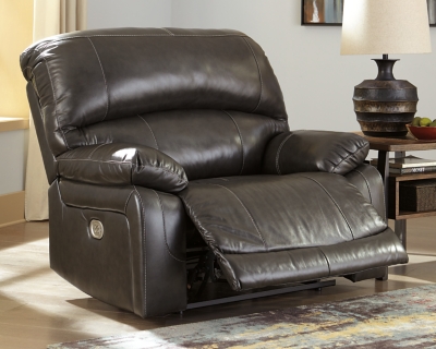 Fashion-forward style. Sumptuous leather feel and appeal. Total comfort at your fingertips. It’s all yours for the taking with the Hallstrung power recliner with adjustable headrest. Wrapped in an attractive gray upholstery, this decidedly contemporary power recliner tantalizes the senses in so many ways. Rest assured, the wide seating area is covered in 100% leather for your pleasure, while a skillfully matched faux leather on the exterior makes luxury affordable. Upping the comfort with 44" high back styling, this power recliner truly caters from head to toe. An Easy View™ power adjustable headrest allows you to lean back while propping up your head—perfect for chilling out in front of the TV—while an extended ottoman lets you stretch out all the more. And with a USB port in the power control panel, you hardly have to move a muscle to stay powered up.High-resiliency foam cushions wrapped in thick poly fiber | Corner-blocked frame with metal reinforced seat | One-touch power control with adjustable positions | 44" high back design | Attached back and seat cushions | Easy View™ power adjustable headrest | Leather interior upholstery; polyester/vinyl exterior upholstery | Extended ottoman for enhanced comfort | Includes USB charging port in the power control | Power cord included; UL Listed | Estimated Assembly Time: 15 Minutes