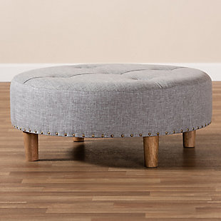 Chic and versatile, this ottoman is designed for the modern home. Upholstered in a soft polyester fabric that displays a subtle cross-hatch weave for a natural earthy feel. The neutral upholstery is complemented by sturdy wood legs showcasing the rustic beauty of the woodgrains. Button tufting on the top and brass-tone nailhead trim along the lower edge add a touch of elegance. Use this versatile ottoman as a coffee table, footstool or extra seating for guests as the need arises.Engineered wood frame | Solid wood legs with natural finish | Light gray polyester upholstery | Assembly required